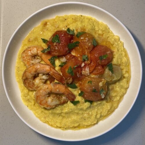 Corn polenta with shrimp and tomatoes, served with fresh basil on top.