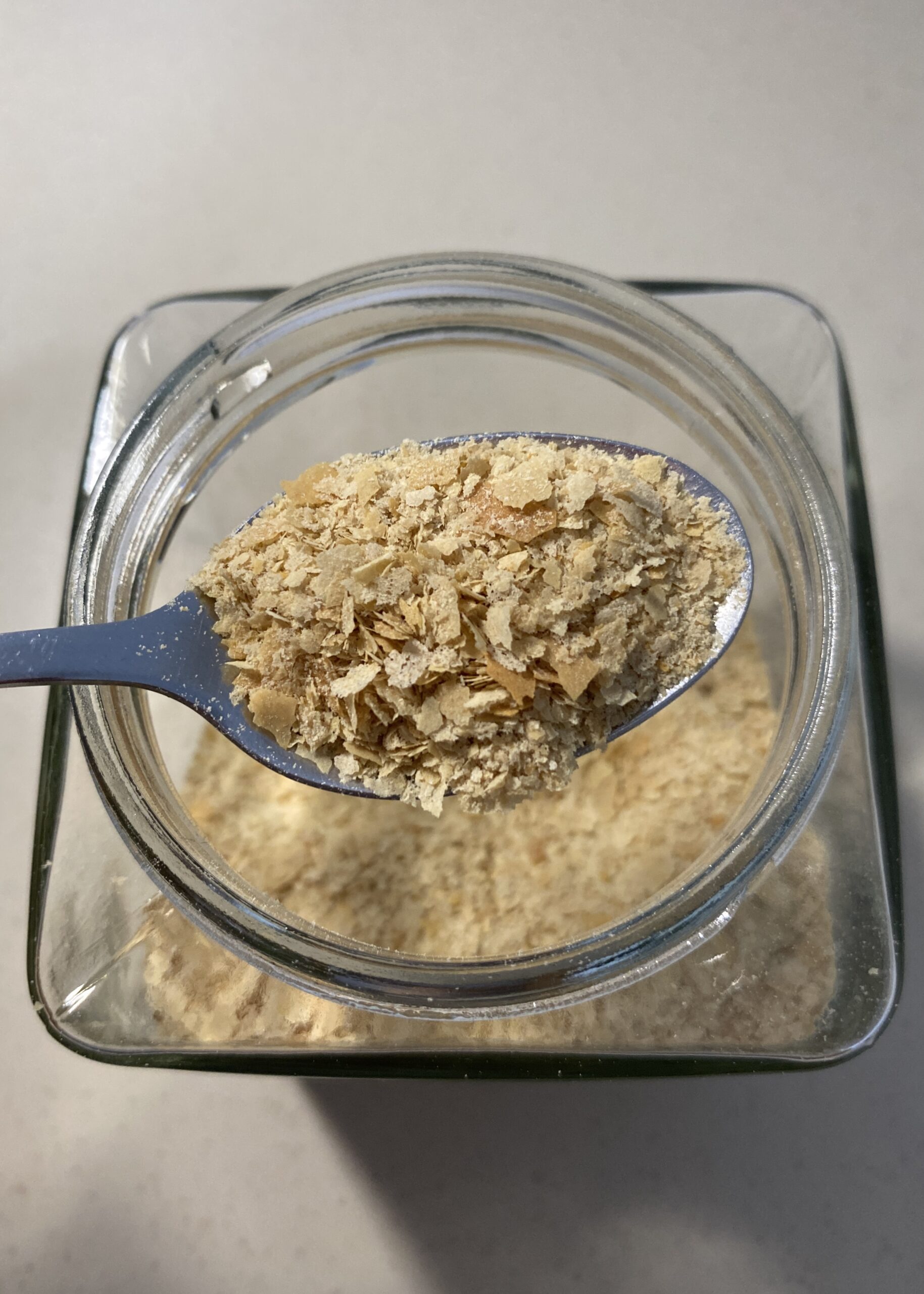 Close-up of a spoon filled with golden nutritional yeast flakes